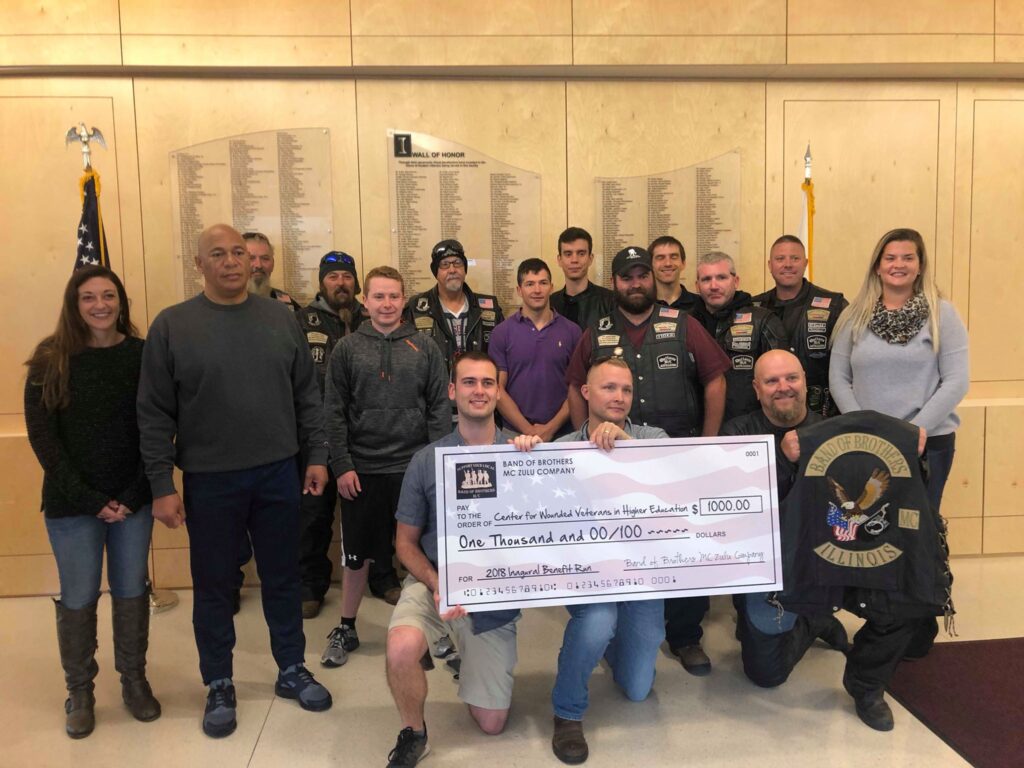 Band of Brothers Motorcycle Group members crowd around students and staff with a large check from their donations to the Center. 